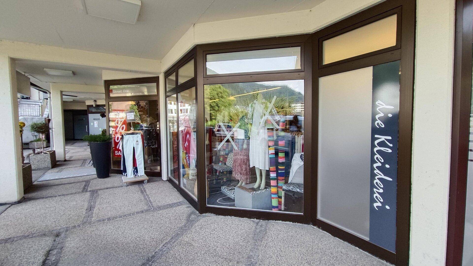Seitenansicht des Ladengeschäfts mit großen Schaufenstern, die Kleidung und Mannequins präsentieren.
