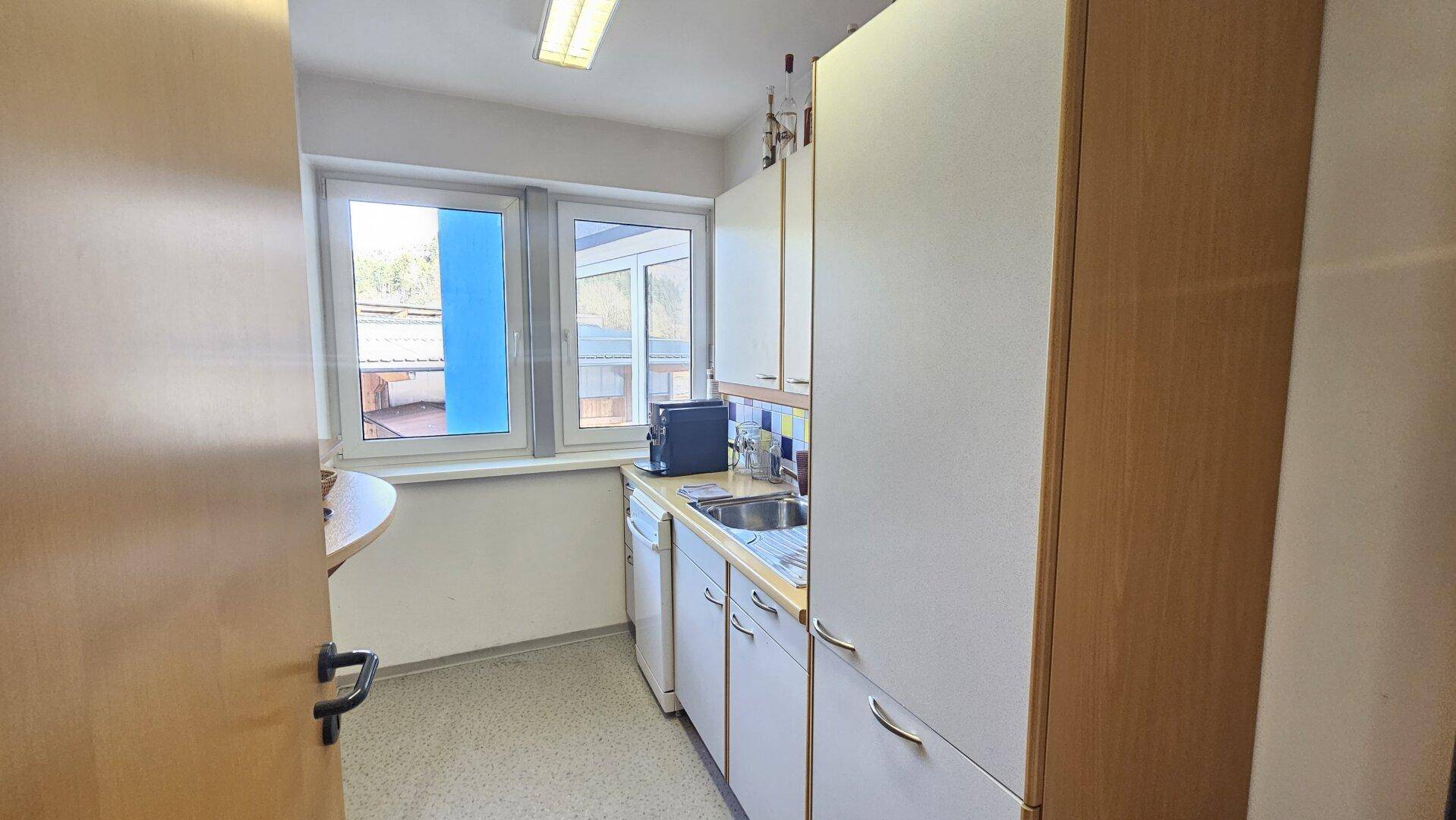 Funktionale Küchenzeile mit weißen Schränken, Spüle und Fenster, ideal für eine schnelle Zubereitung.