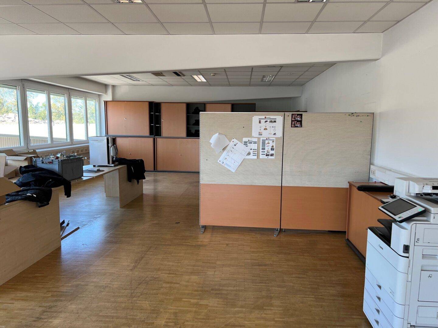 Geräumiges Büro mit Holzfußboden, Schränken und Trennwänden, bereit zur Einrichtung.
