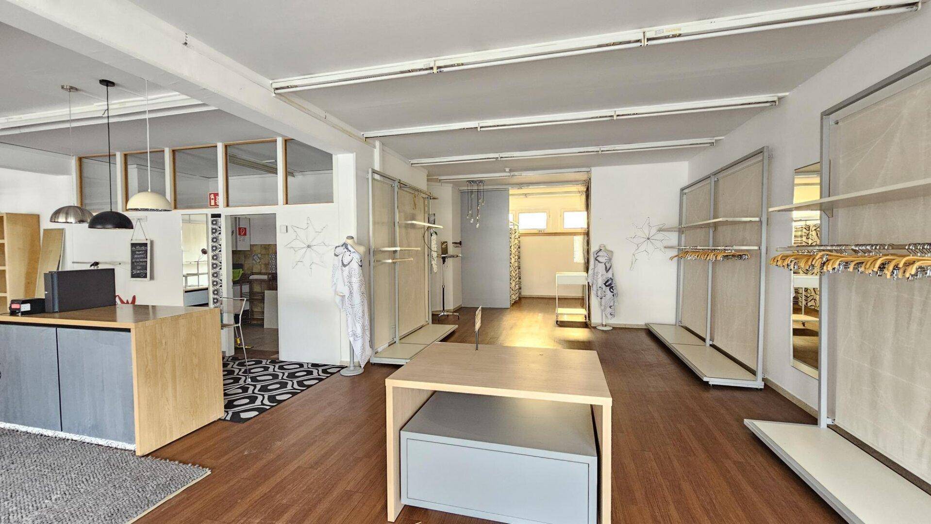 Weitläufiger Verkaufsbereich mit flexiblen Präsentationsflächen und Holzboden, bereit für neue Konzepte.