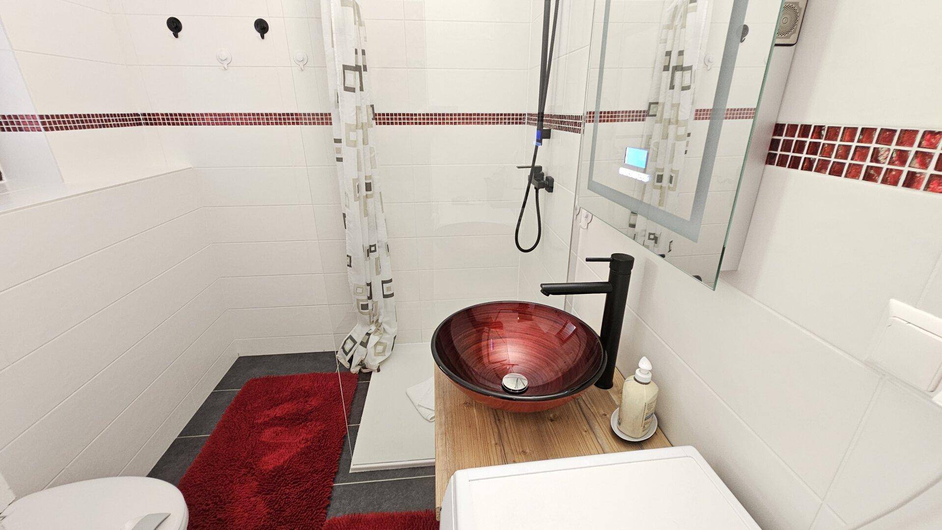Modernes Badezimmer mit Dusche, WC und stilvollem Aufsatzwaschbecken.