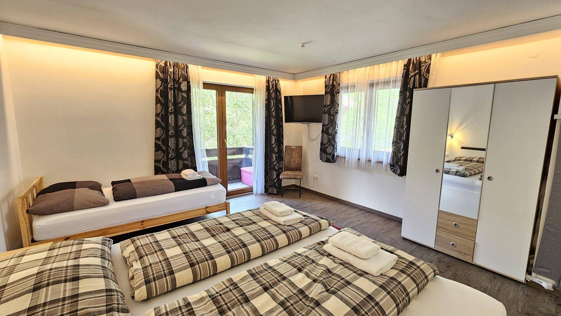 Geräumiges Schlafzimmer mit Doppelbett, Einzelbett und großem Kleiderschrank.