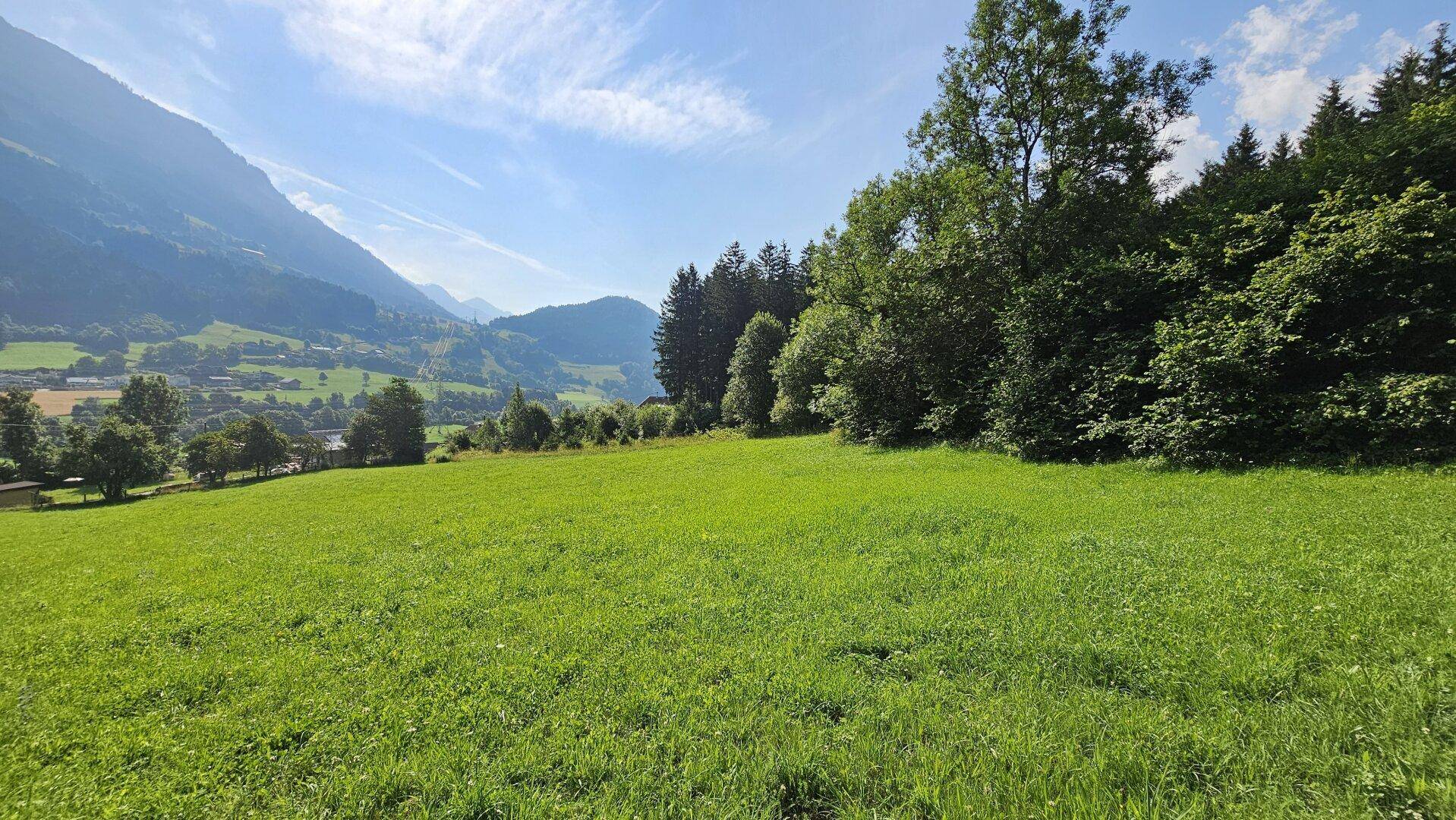 Gepflegte grüne Rasenfläche mit weitem Blick auf ein malerisches Tal und die umliegenden Berge.