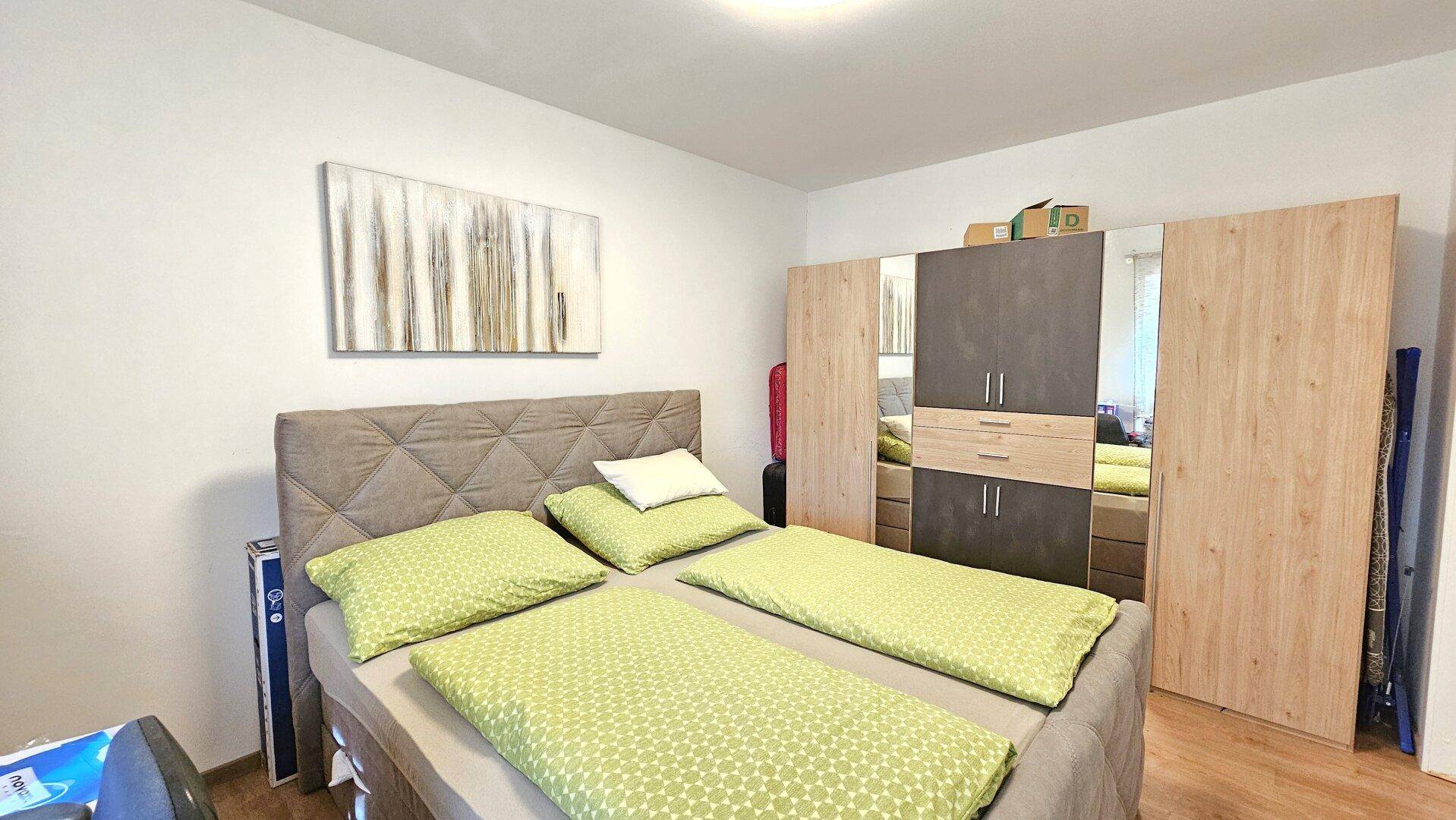 Schlafzimmer mit Doppelbett, Holzboden und großem Kleiderschrank.