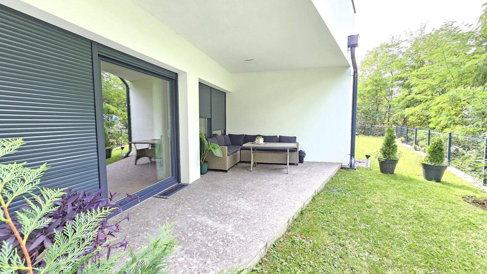 Geräumige Terrasse mit Sitzgruppe und Blick auf den grünen Gartenbereich.