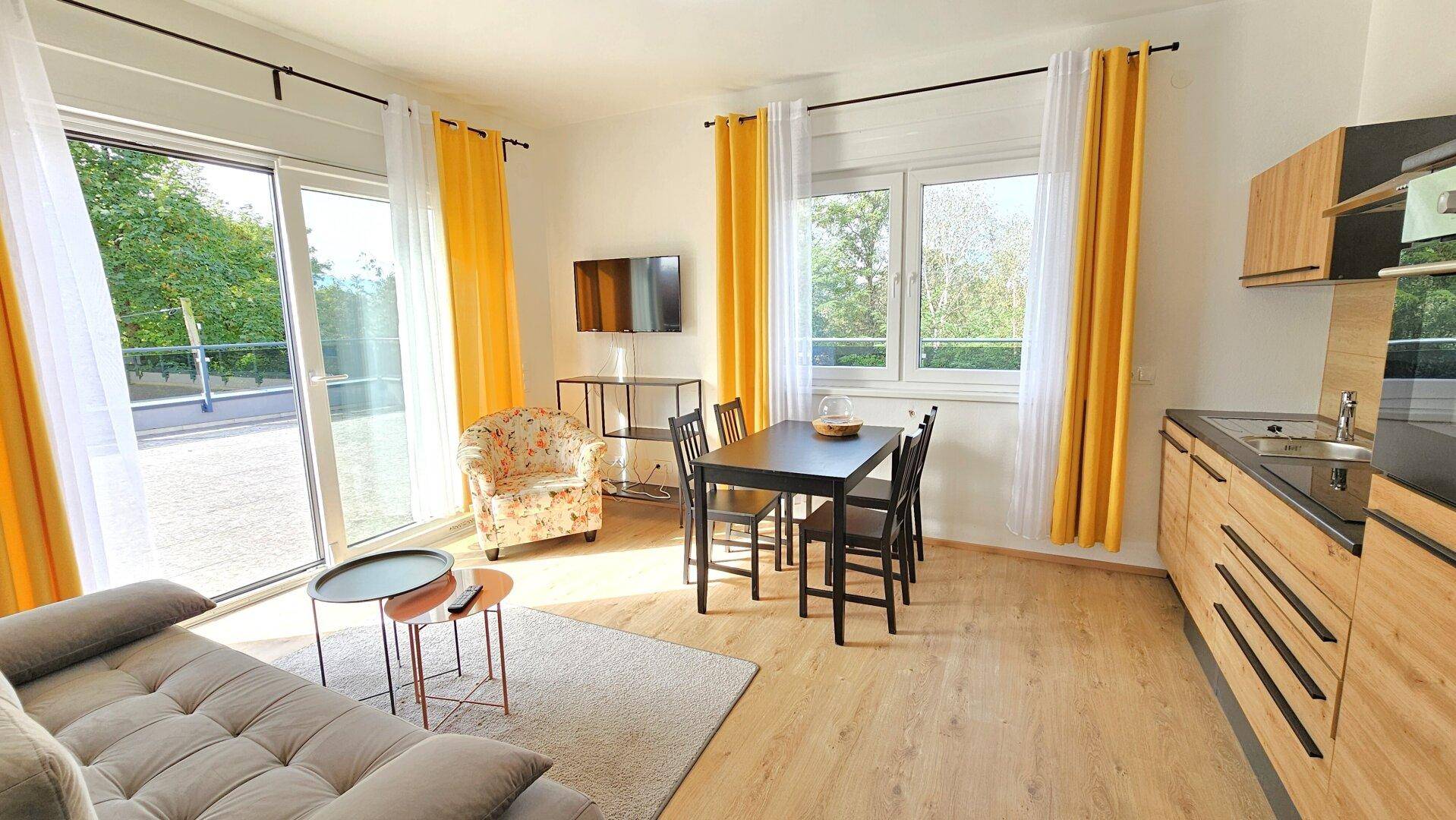 Offener Wohnbereich mit Küchenzeile, Essplatz und Zugang zur Terrasse.