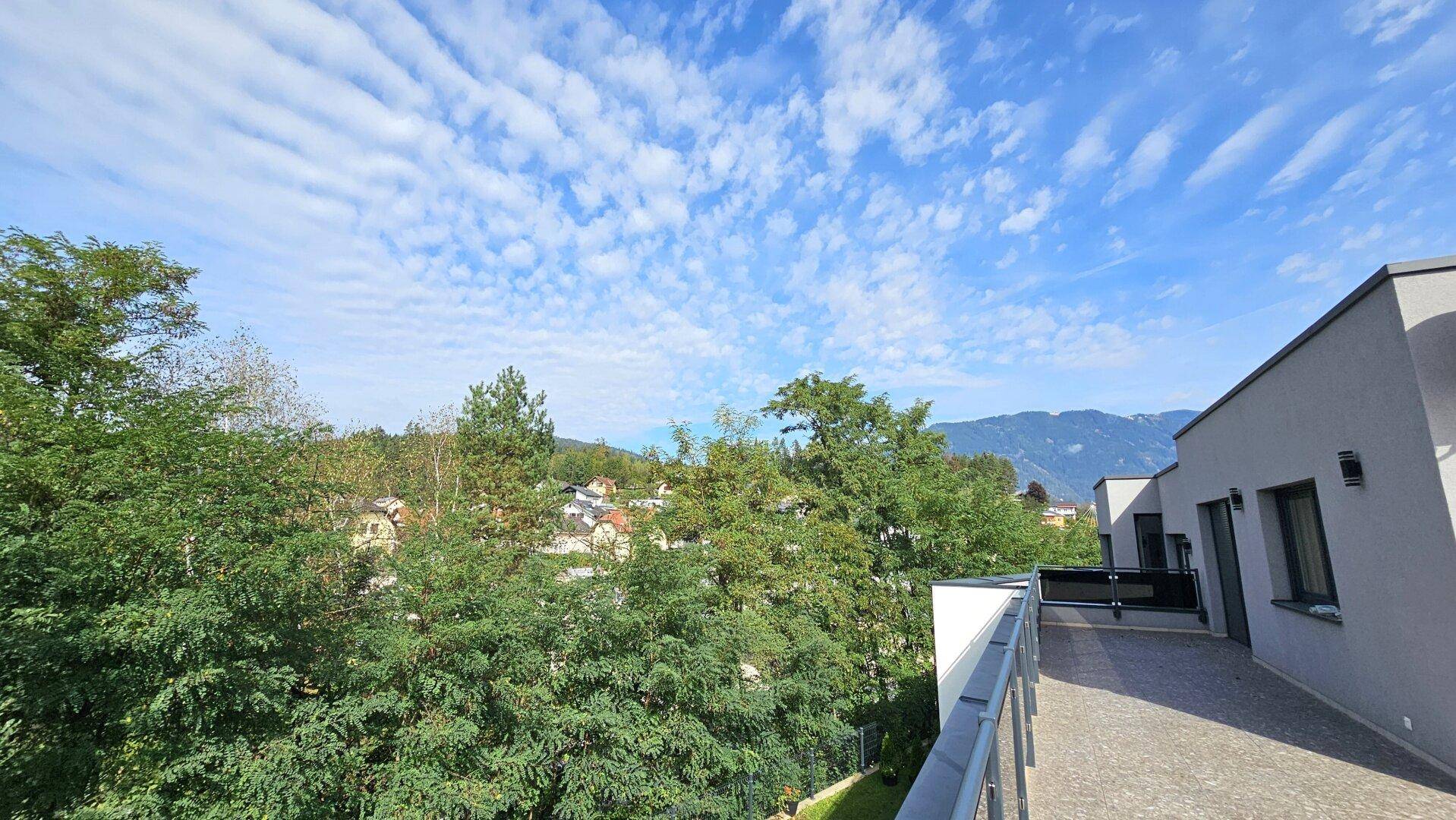Panoramablick auf die grüne Umgebung und die Berge von der Terrasse aus.