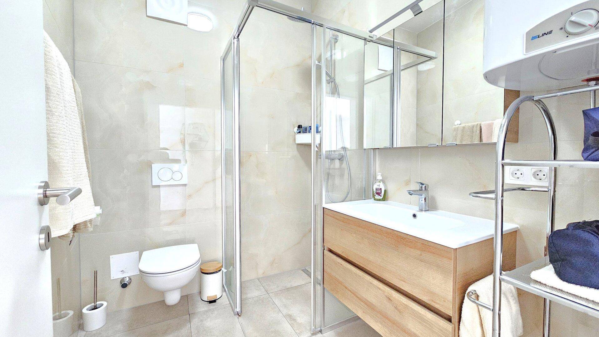 Modernes Badezimmer mit Duschkabine, WC und Holzwaschtisch.
