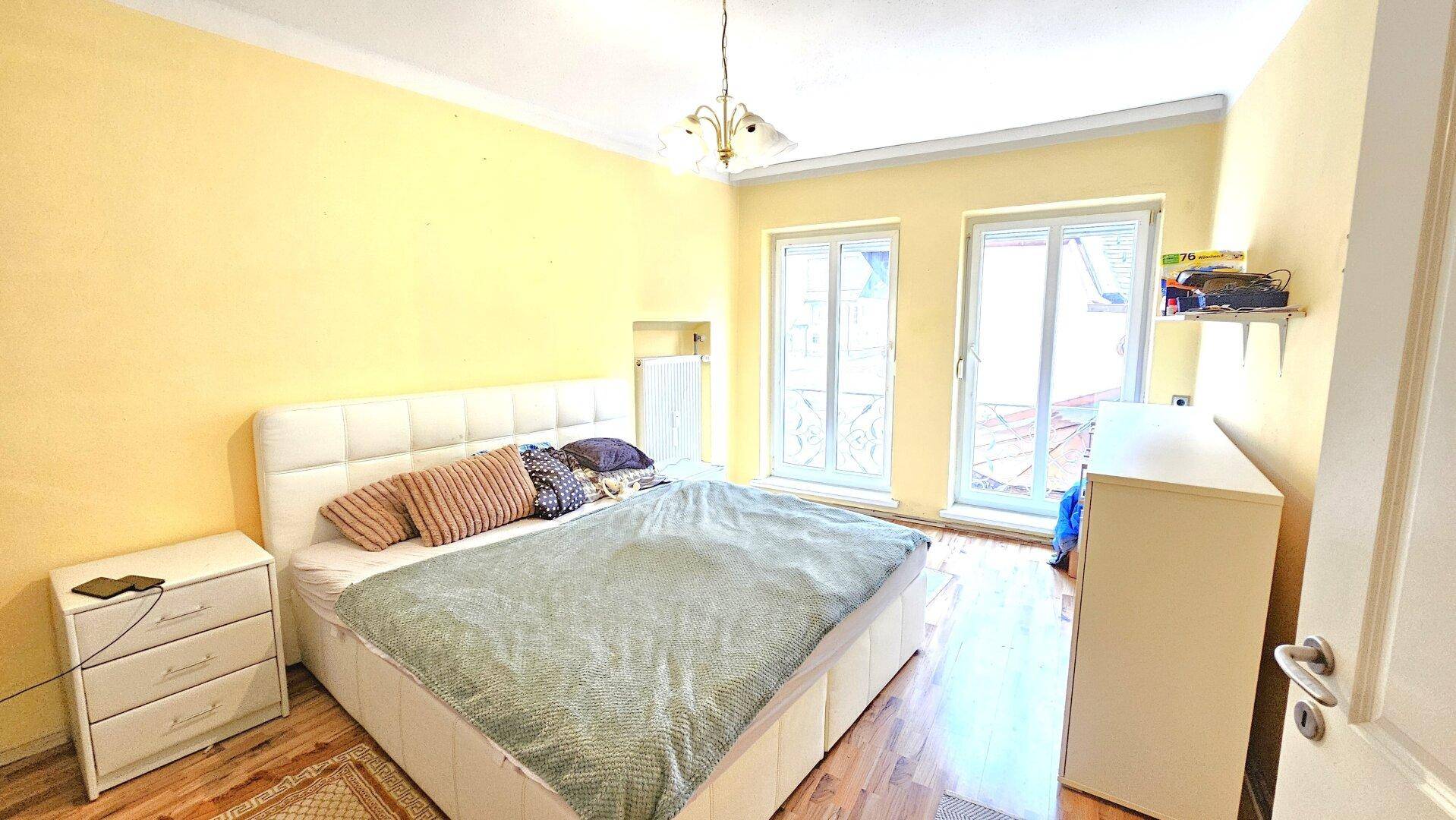 Schlafzimmer mit gelben Wänden, Doppelbett und Zugang zu einem Außenbereich.