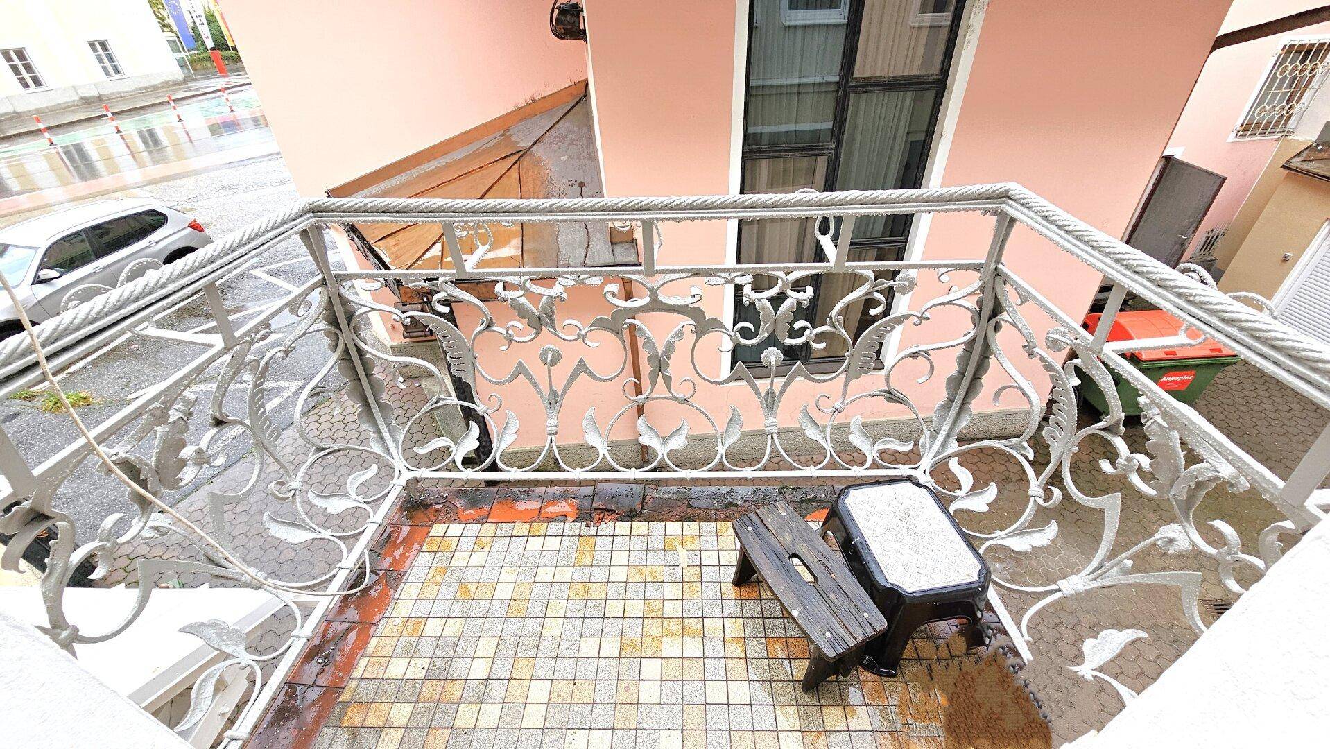 Kleiner Balkon mit kunstvollem Metallgeländer und Blick auf die Straße.
