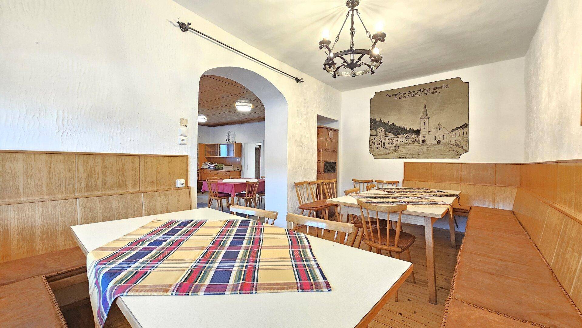 Gemütliche Gaststube mit Holzbänken, Tischen und traditioneller Wanddekoration.