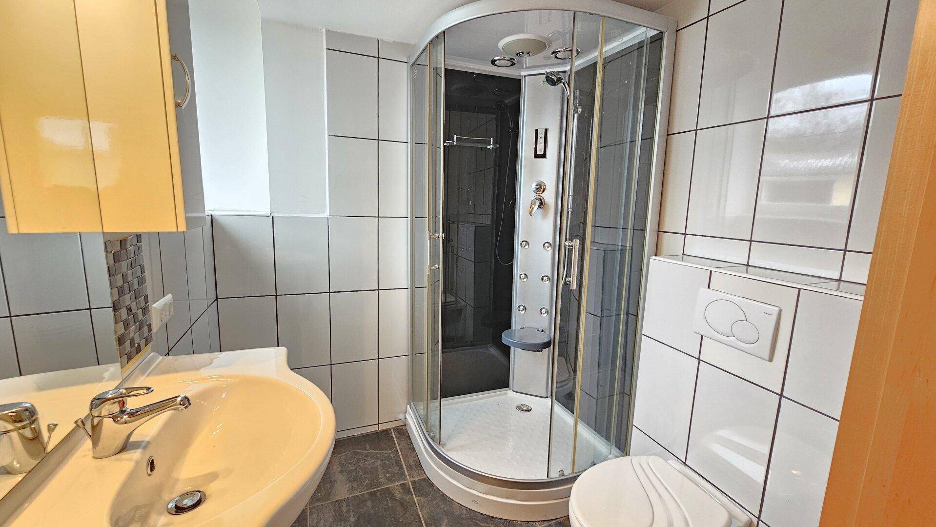 Modernes Badezimmer mit Duschkabine, Waschbecken und wandhängendem WC.