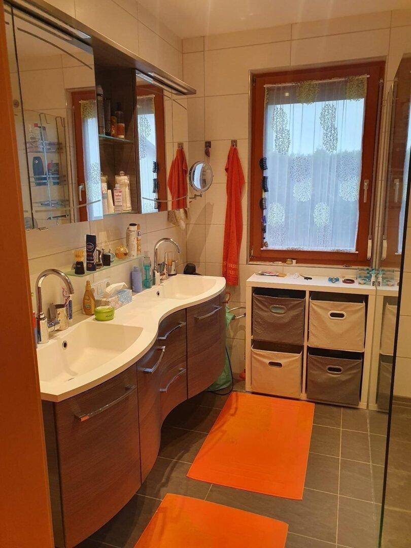 Modernes Badezimmer mit Doppelwaschbecken, großem Spiegel und Fenster.