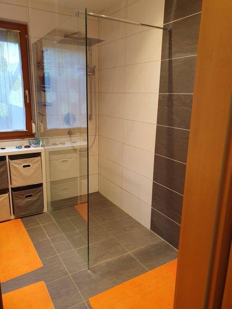 Modernes Badezimmer mit ebenerdiger Dusche, weißen Fliesen und Fenster.