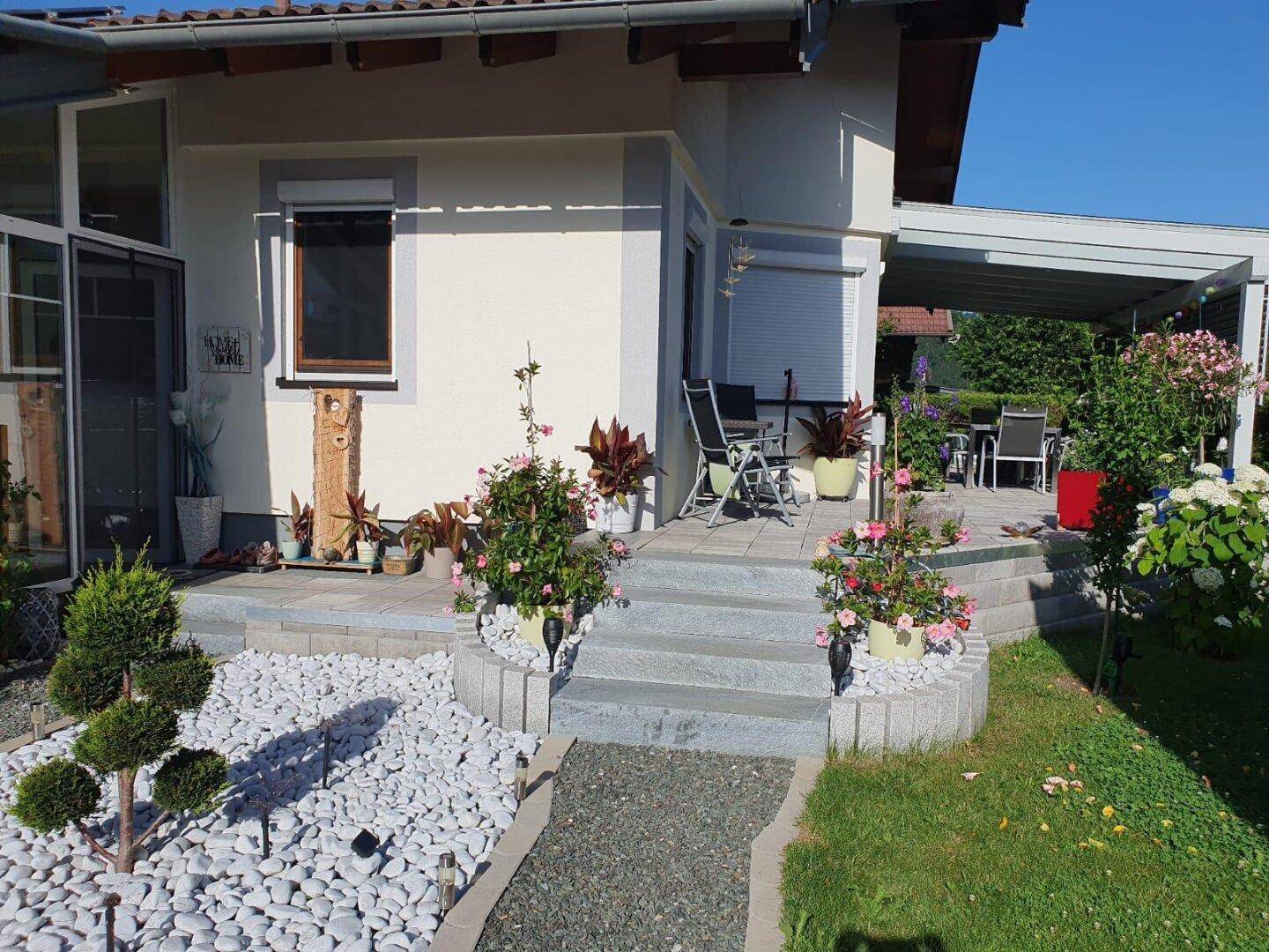 Gepflegter Vorgarten mit Zierpflanzen, Kiesbeet und Zugang zur Terrasse.