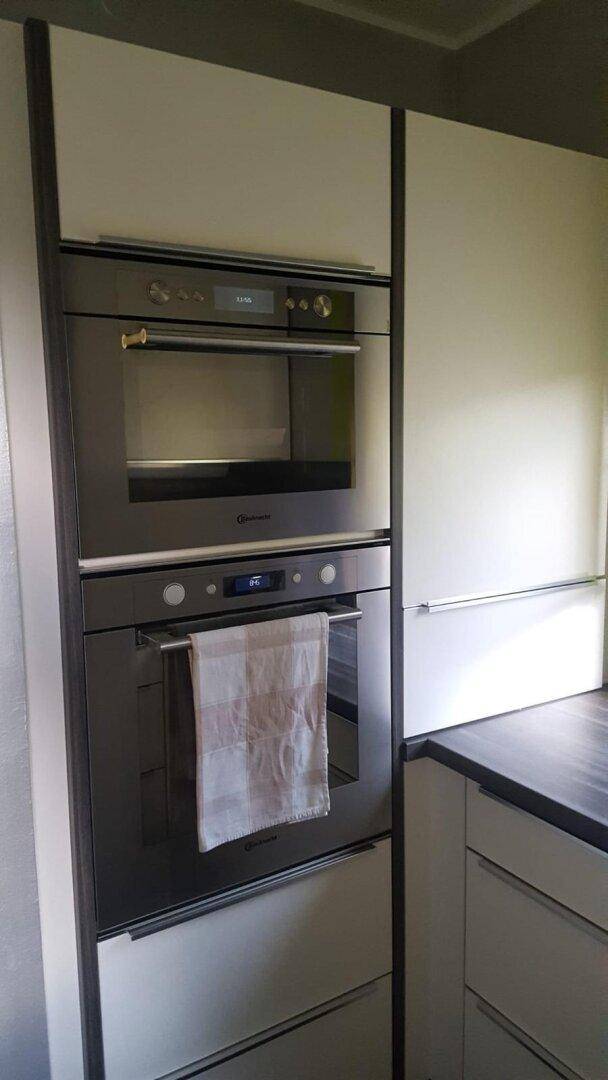 Integrierte Küchenzeile mit Backofen und Mikrowelle in Hochschränken.