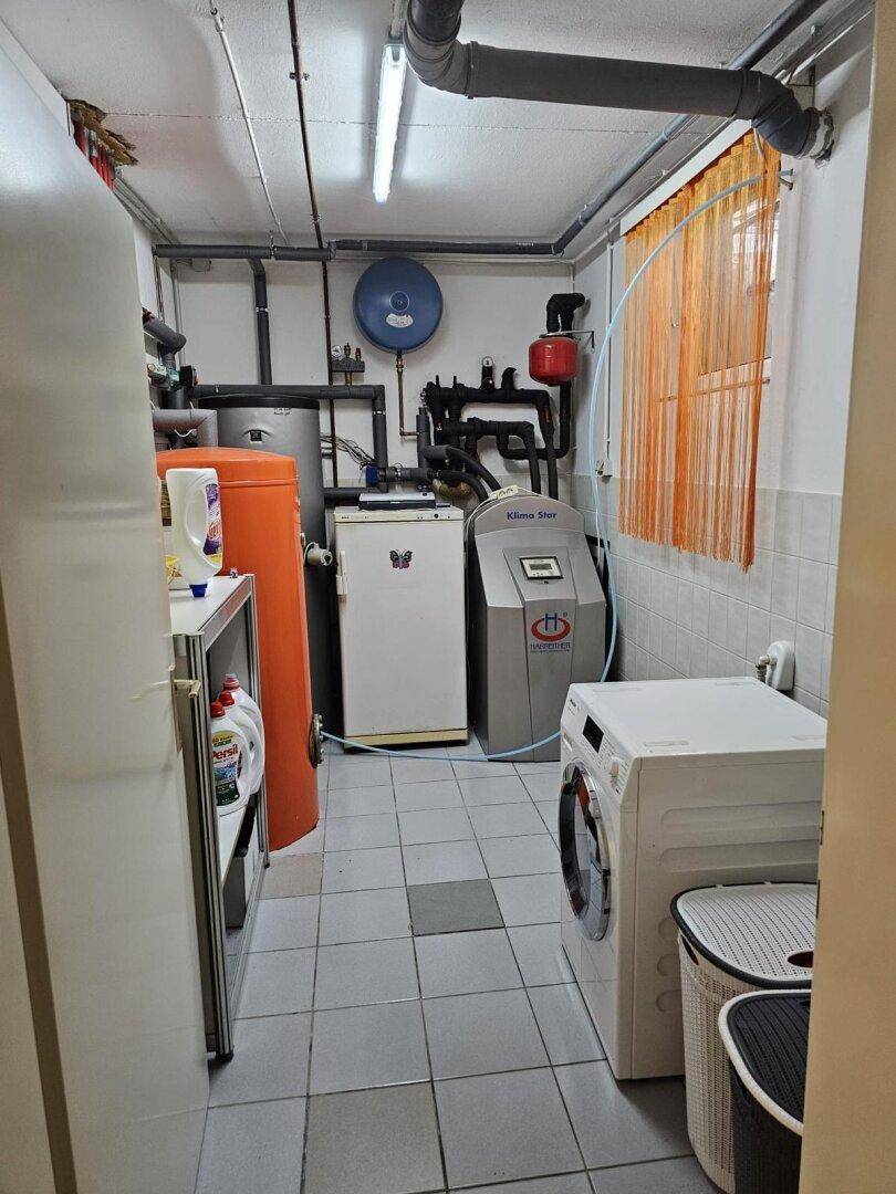 Hauswirtschaftsraum mit Heizungsanlage, Waschmaschine und sichtbaren Installationen.