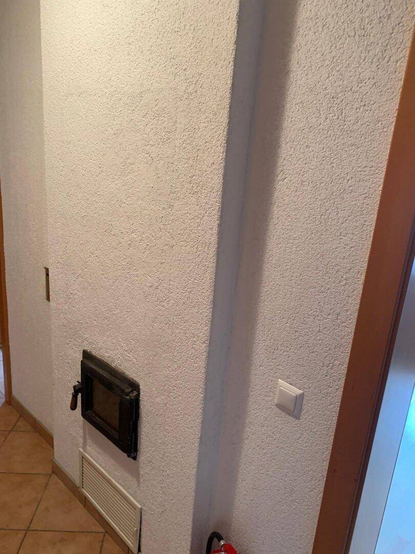 Wand mit integriertem Kamineinsatz, der eine zusätzliche Wärmequelle bietet.