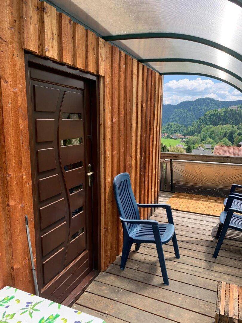 Überdachter Balkon mit Sitzgelegenheiten und weitem Blick auf die grüne Umgebung.
