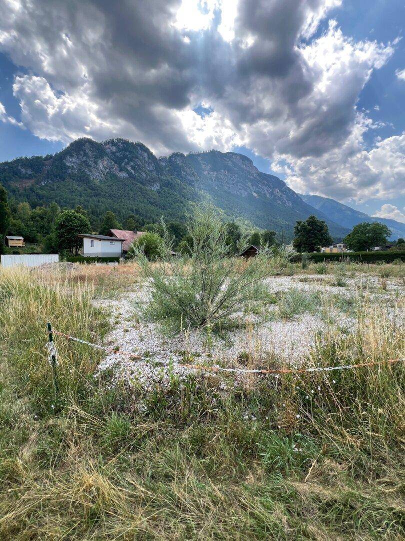 Grundstück mit Blick auf die majestätischen Berge, teilweise von Wolken bedeckt, mit Sonnenstrahlen.