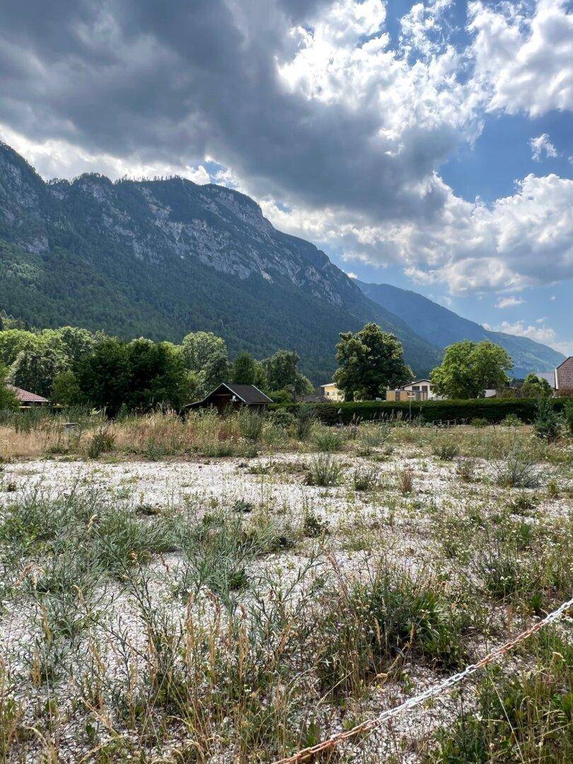 Offenes Grundstück mit weitem Blick auf die Berge und die grüne Umgebung an einem sonnigen Tag.