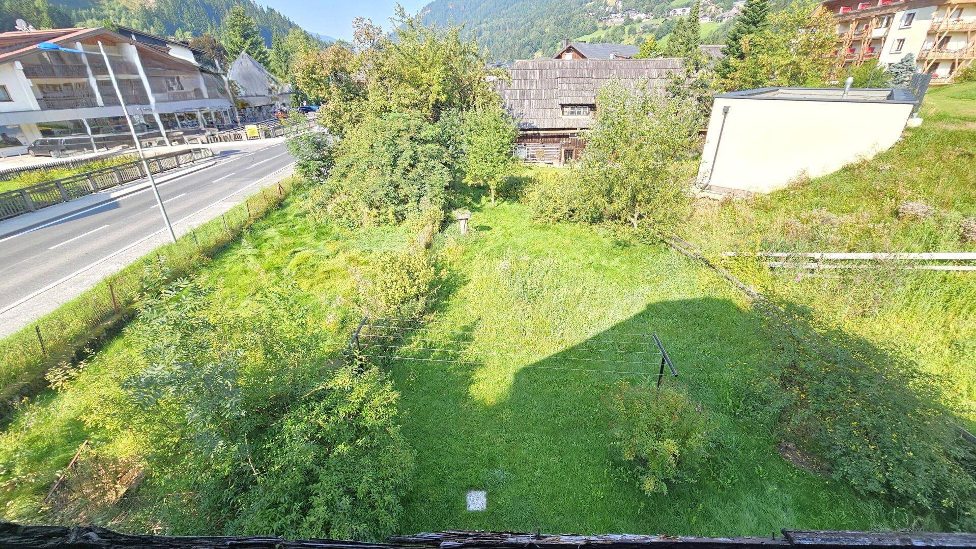 Blick von oben auf den Gartenbereich des Hauses mit angrenzender Straße und umliegender Bebauung.