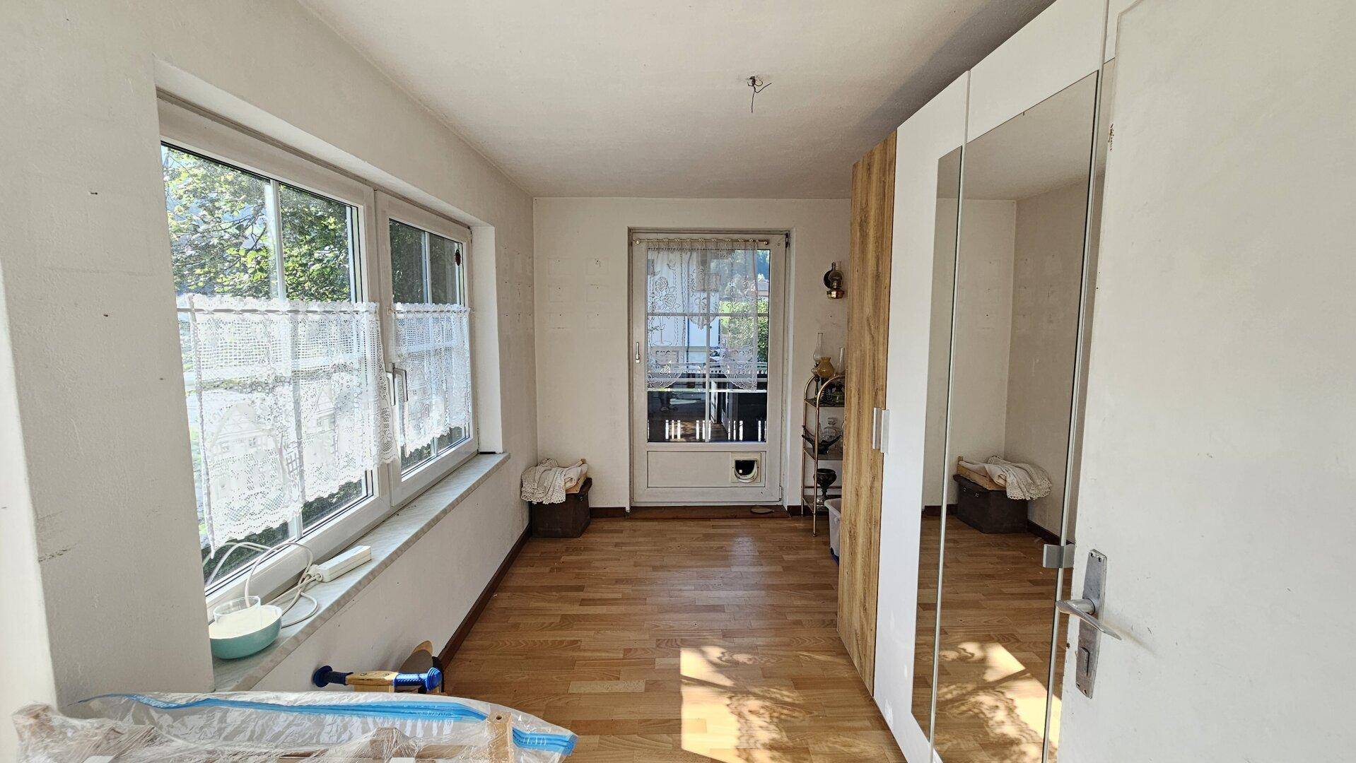 Helles Zimmer mit Laminatboden und einem großen Spiegelschrank, mit Zugang zu einem Balkon.