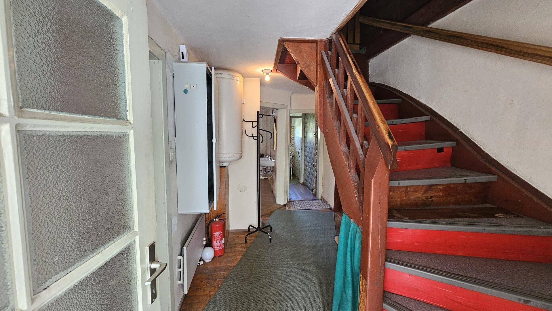 Eingangsbereich mit Holztreppe und Heizungsanlage, der zu den oberen Stockwerken führt.