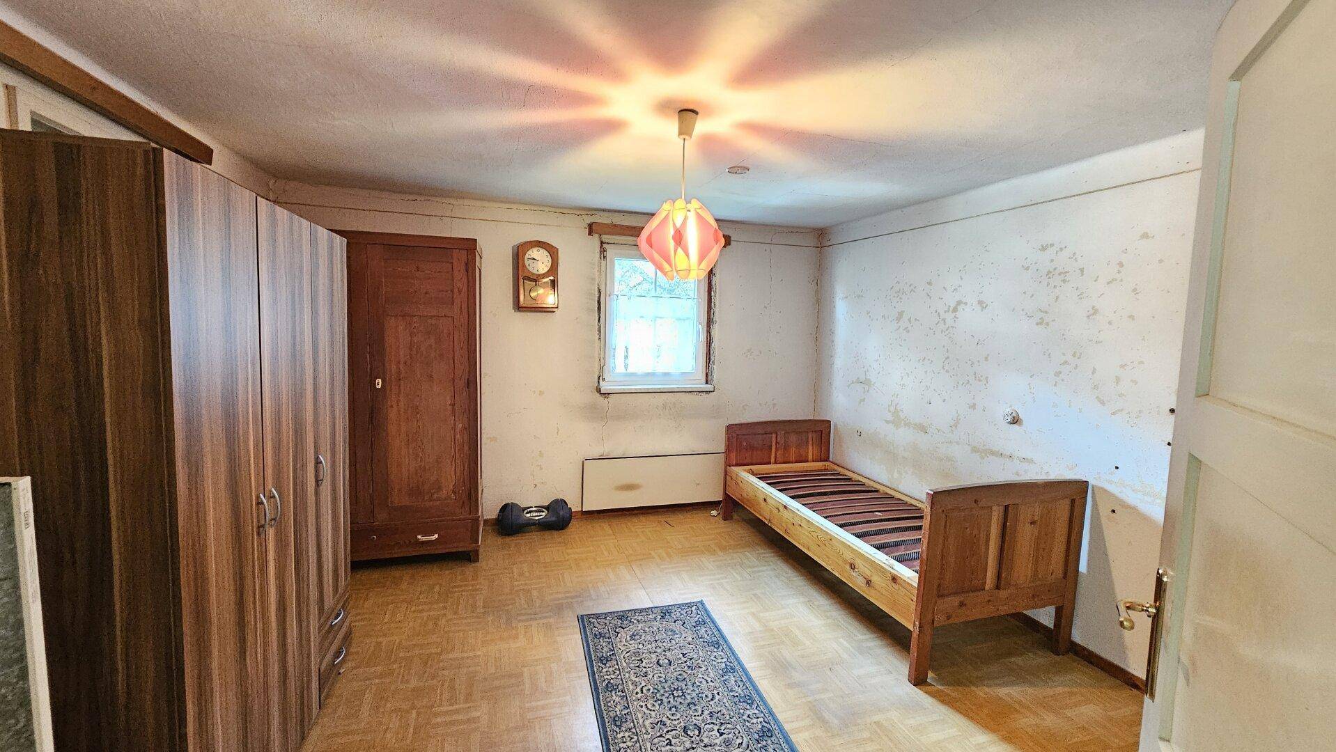 Schlafzimmer mit Einzelbett, Holzschrank und gemusterten Wänden, im traditionellen Stil.