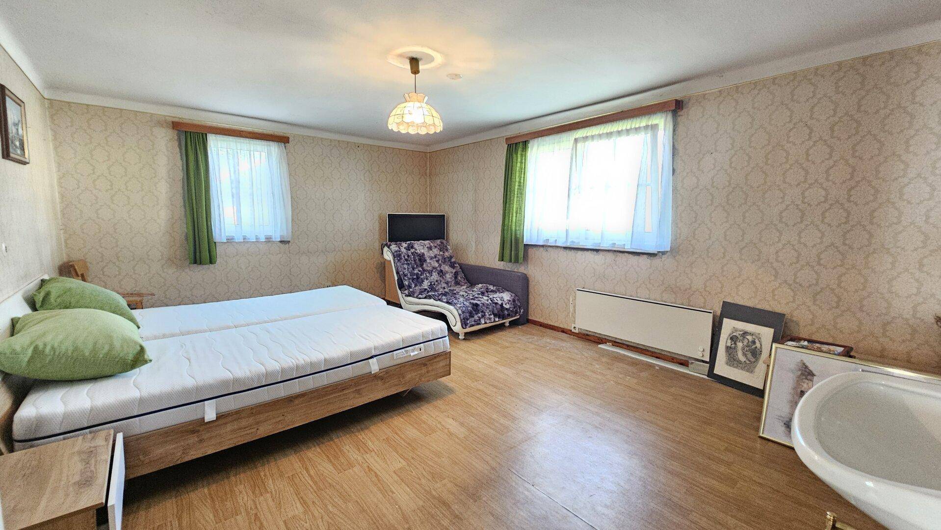Geräumiges Schlafzimmer mit Doppelbett, gemusterter Tapete und zwei Fenstern, im traditionellen Stil.