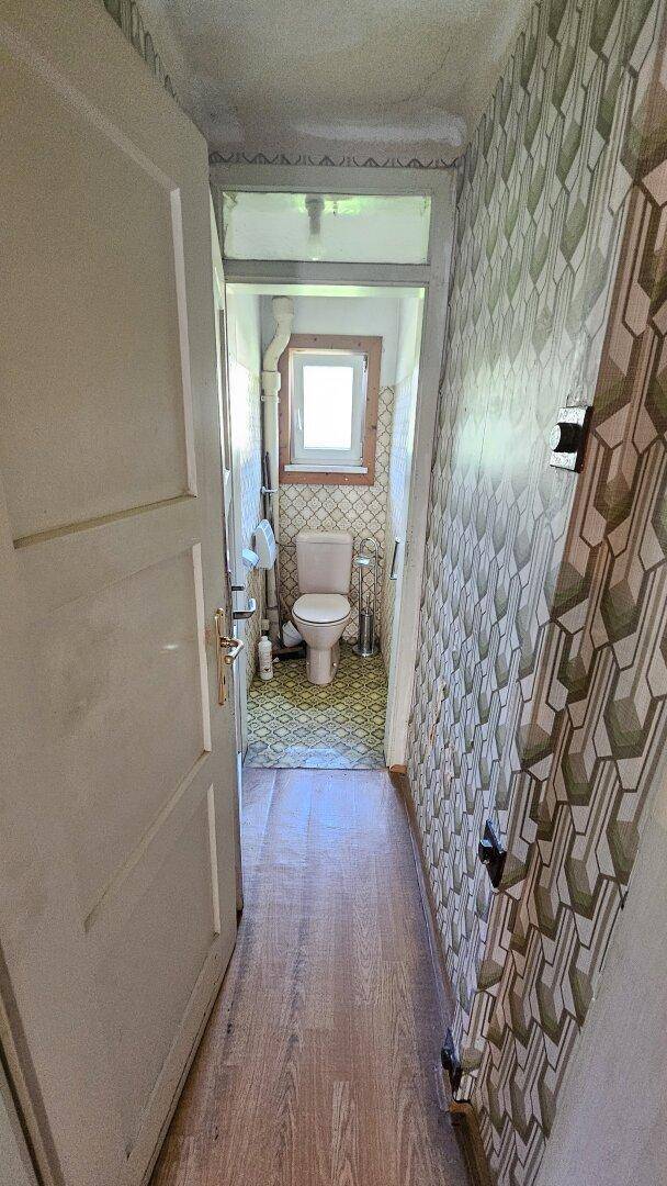Kleines WC mit gemusterter Tapete und Fenster, im traditionellen Stil.
