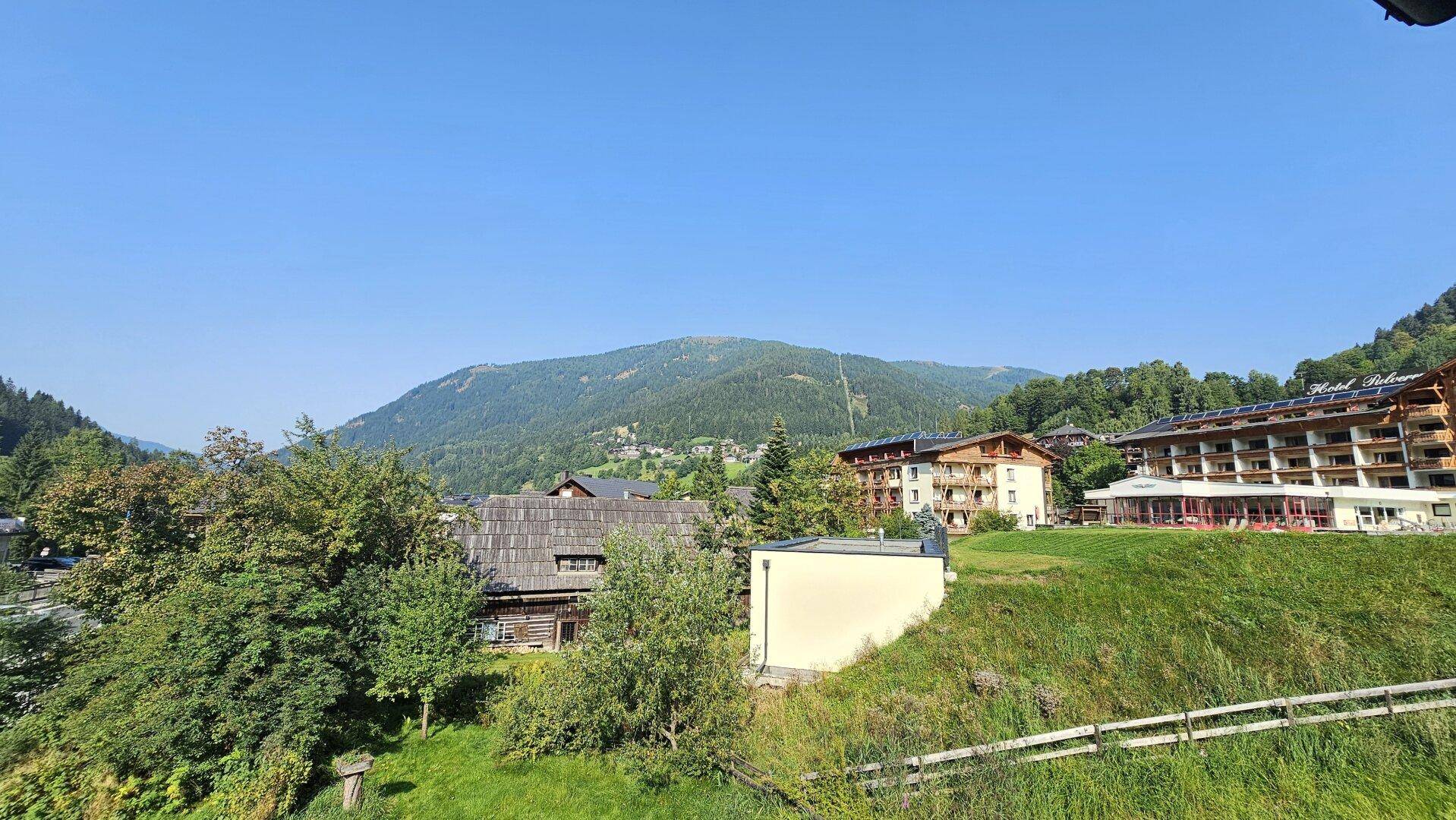 Weitläufiger Blick auf die umliegende Berglandschaft und die Bebauung in der Ferne.