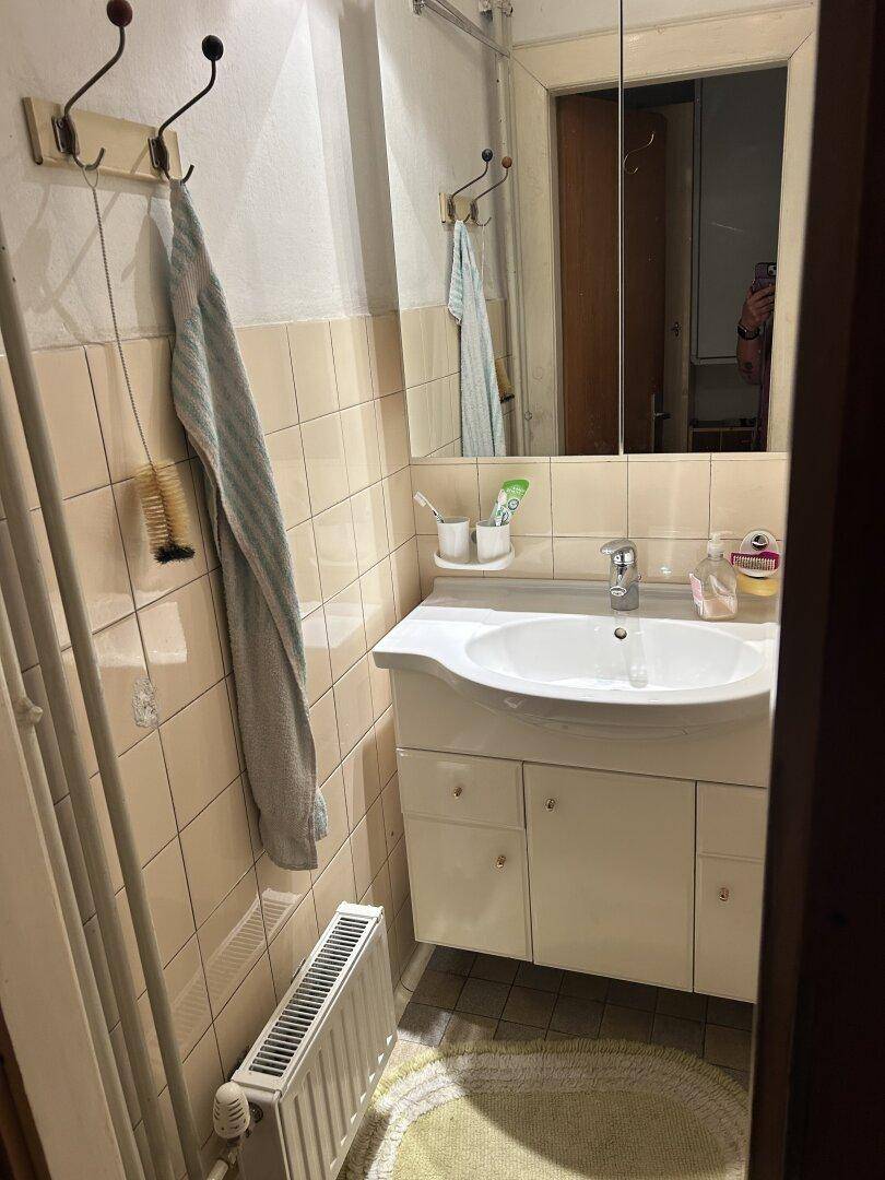Badezimmer mit Waschbecken, Spiegelschrank und Heizkörper.