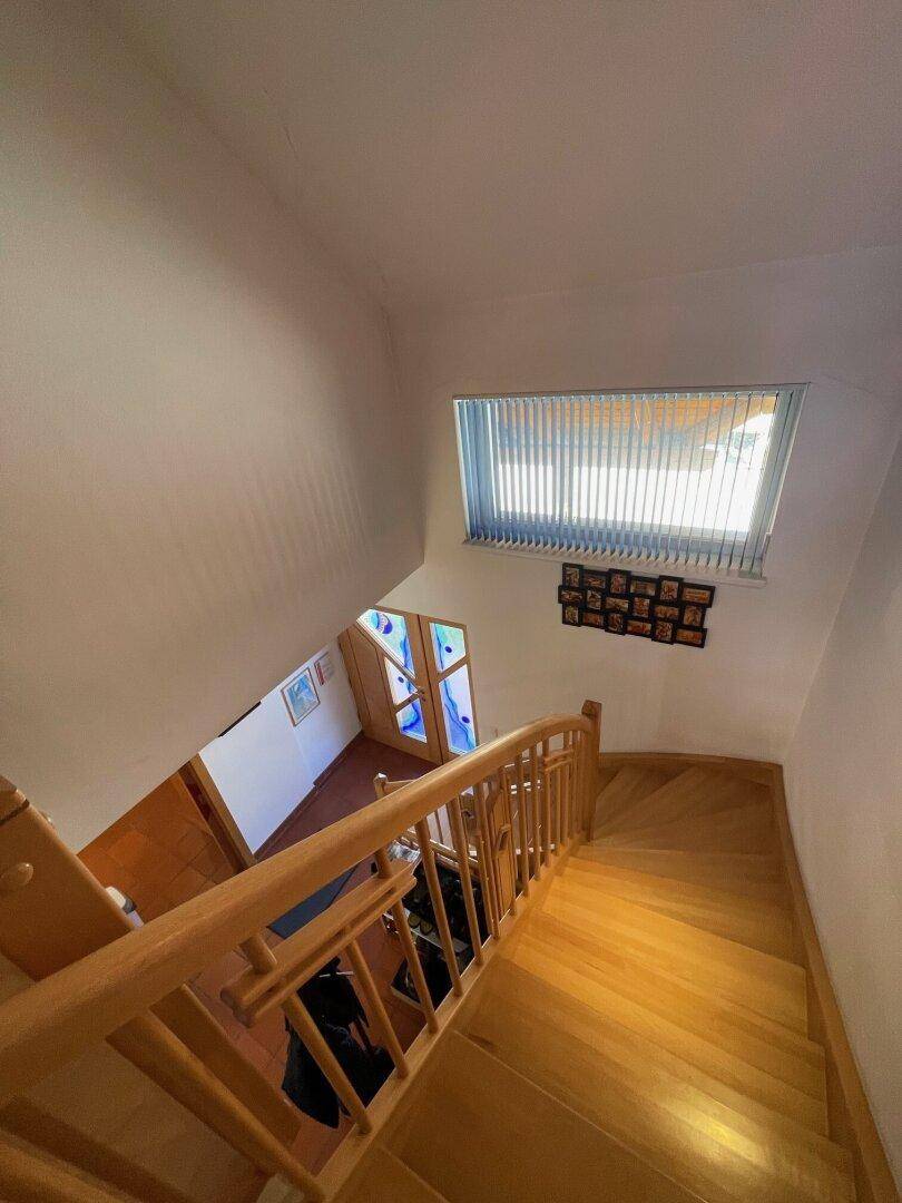 Holztreppe führt nach unten in den Eingangsbereich mit Buntglasfenstern.