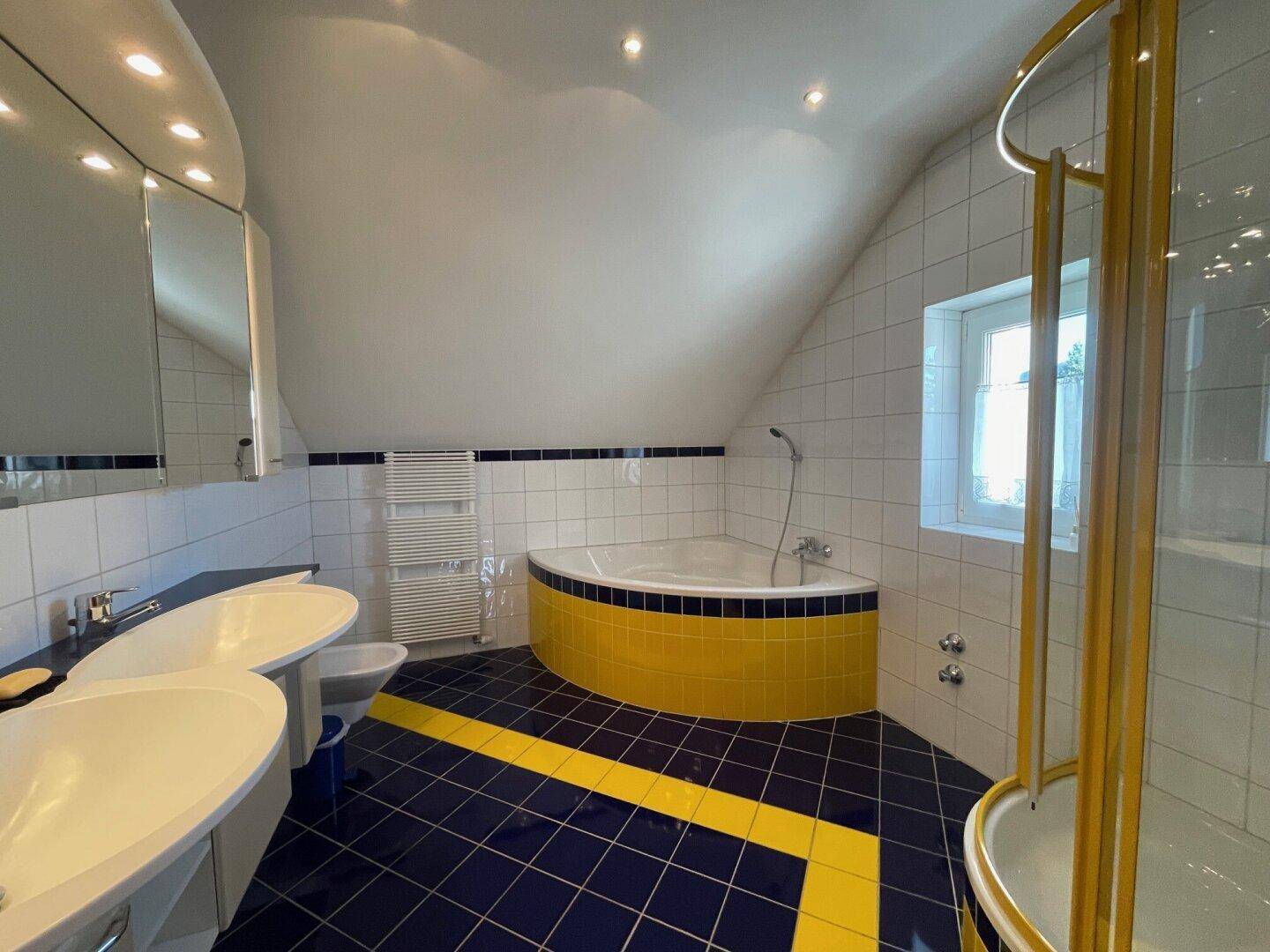 Geräumiges Badezimmer mit Eckbadewanne, Dusche und farbigen Fliesen im Dachgeschoss.