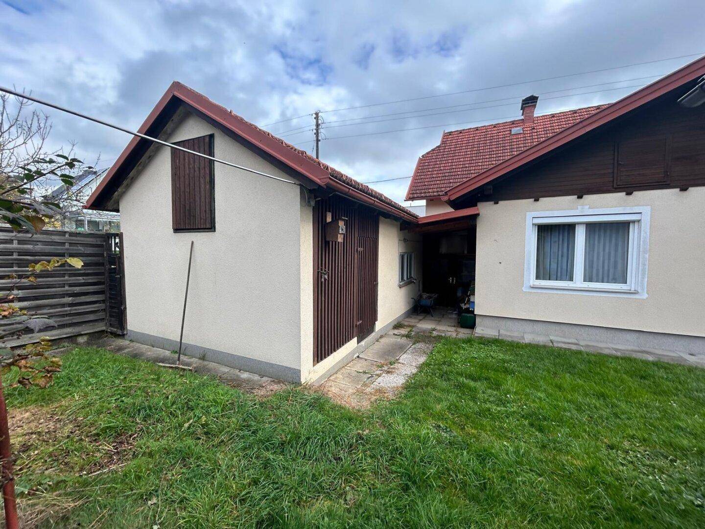 Rückansicht des Hauses mit Nebengebäude und gepflegtem Rasenbereich.