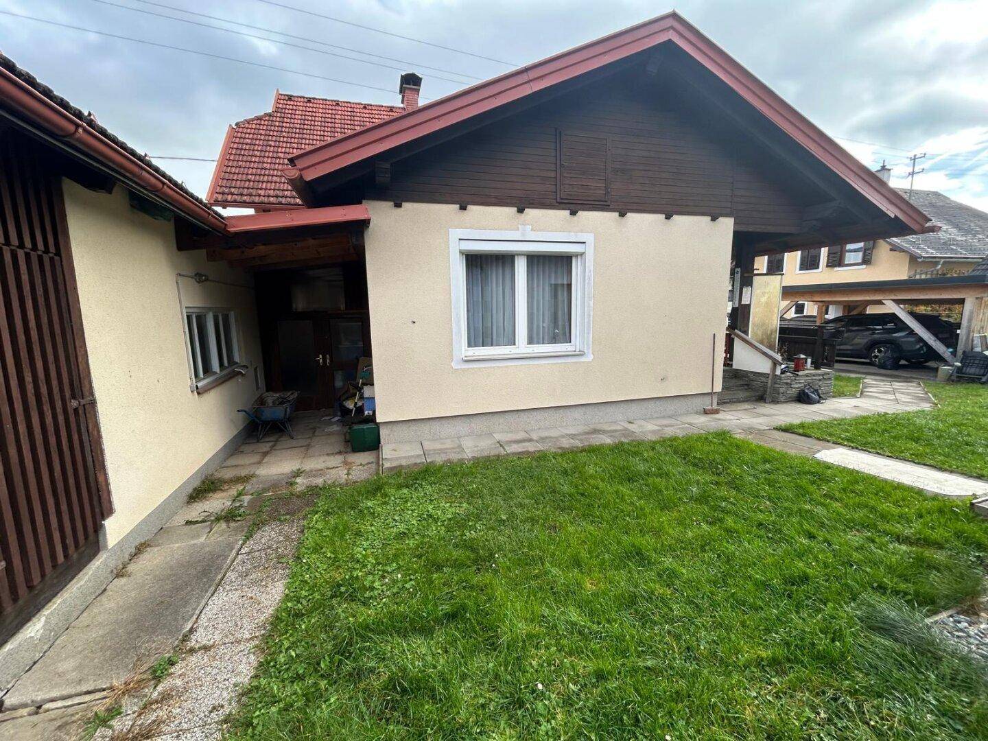 Gartenbereich neben dem Haus mit Rasenfläche und Zugang zum Carport.