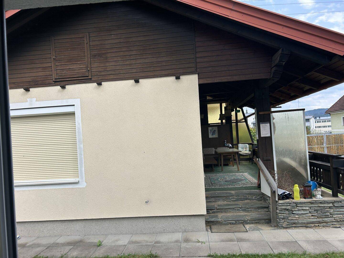 Überdachter Außenbereich mit Sitzgelegenheiten und Blick auf die Umgebung.