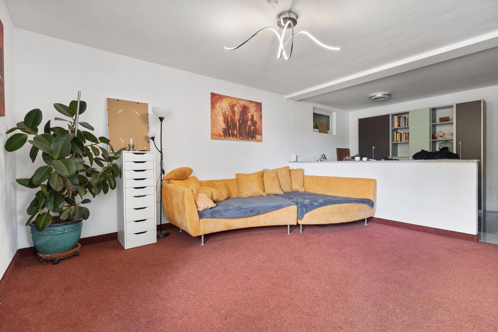 Geräumiges Wohnzimmer mit Teppichboden, gelbem Sofa und offener Gestaltung.