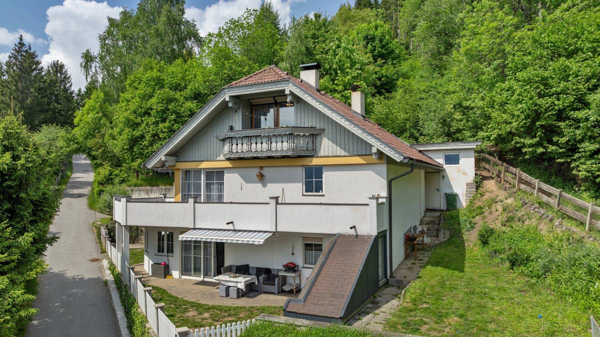 Charmantes Haus in Hanglage mit Balkon, Terrasse und umgeben von viel Grün.
