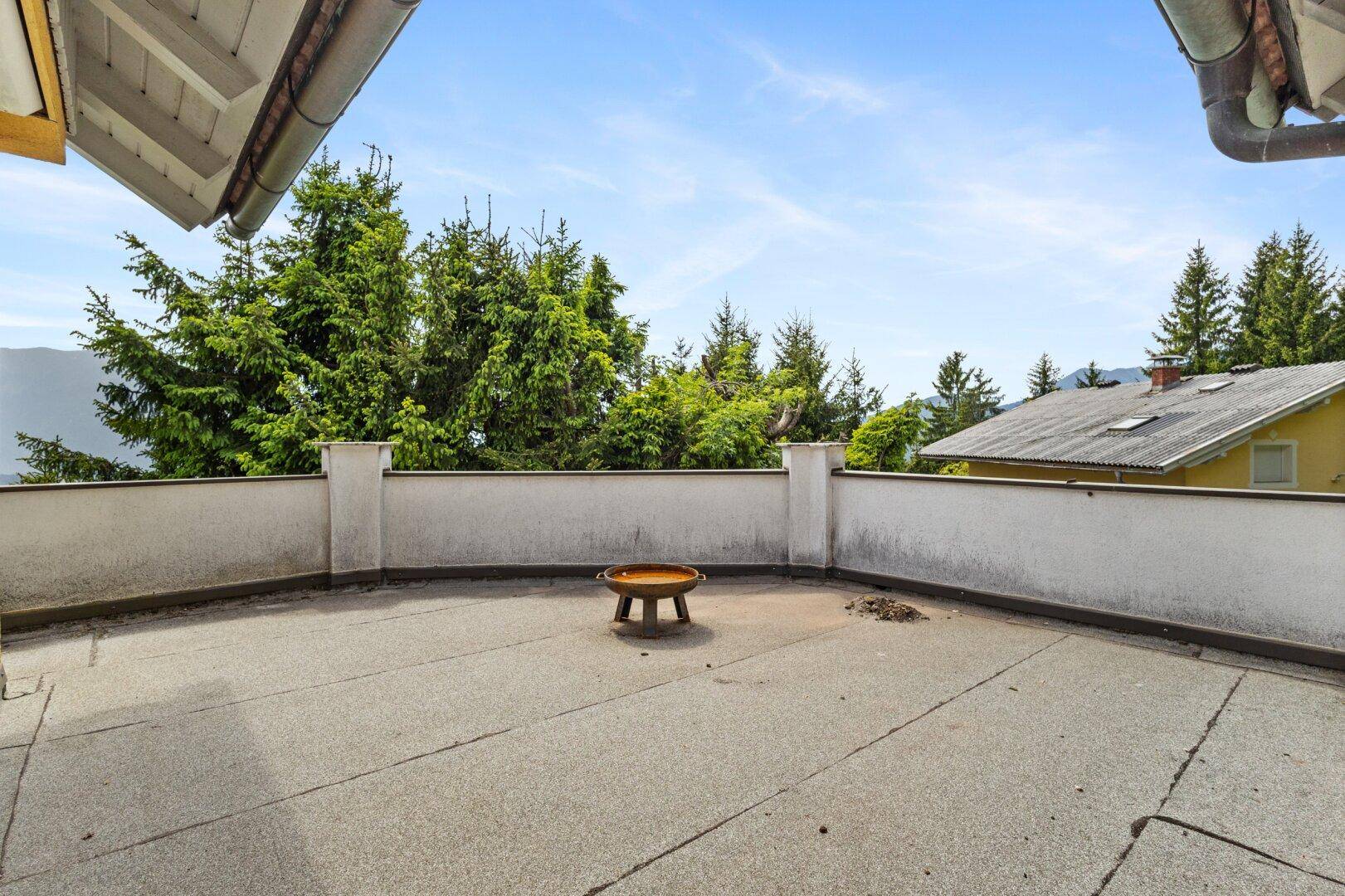Große Dachterrasse mit weitem Blick auf die umliegende Berglandschaft und Bäume.