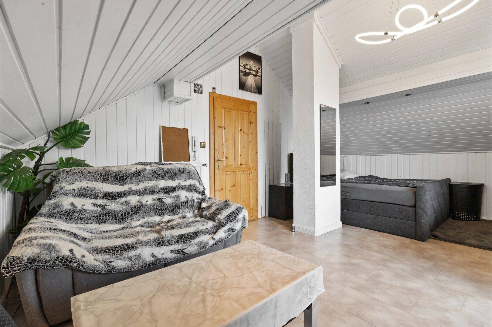 Gemütliches Schlafzimmer im Dachgeschoss mit Schrägdach und Sofa.