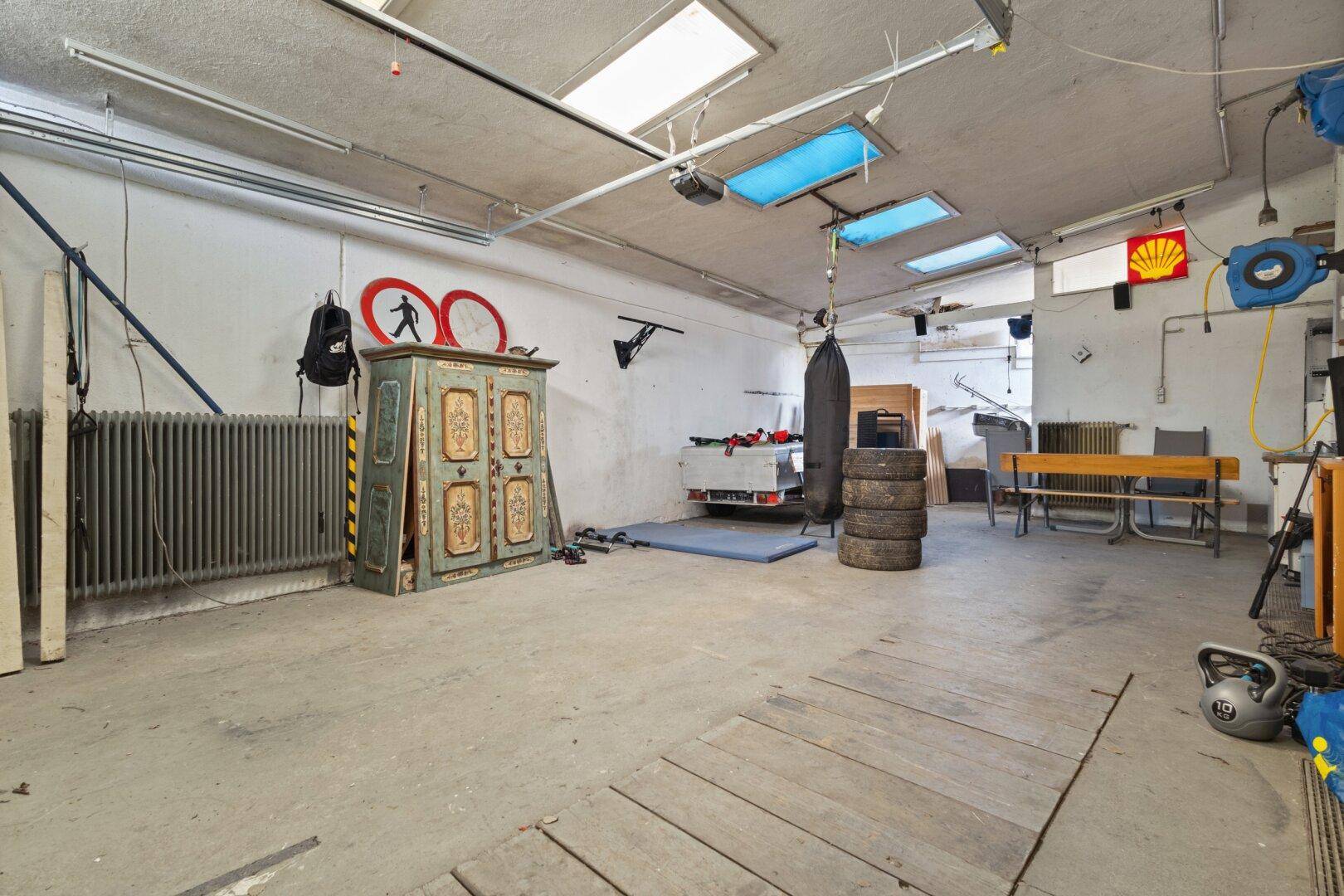 Große Garage mit Werkzeugen, Boxsack und Oberlichtern für zusätzliche Beleuchtung.