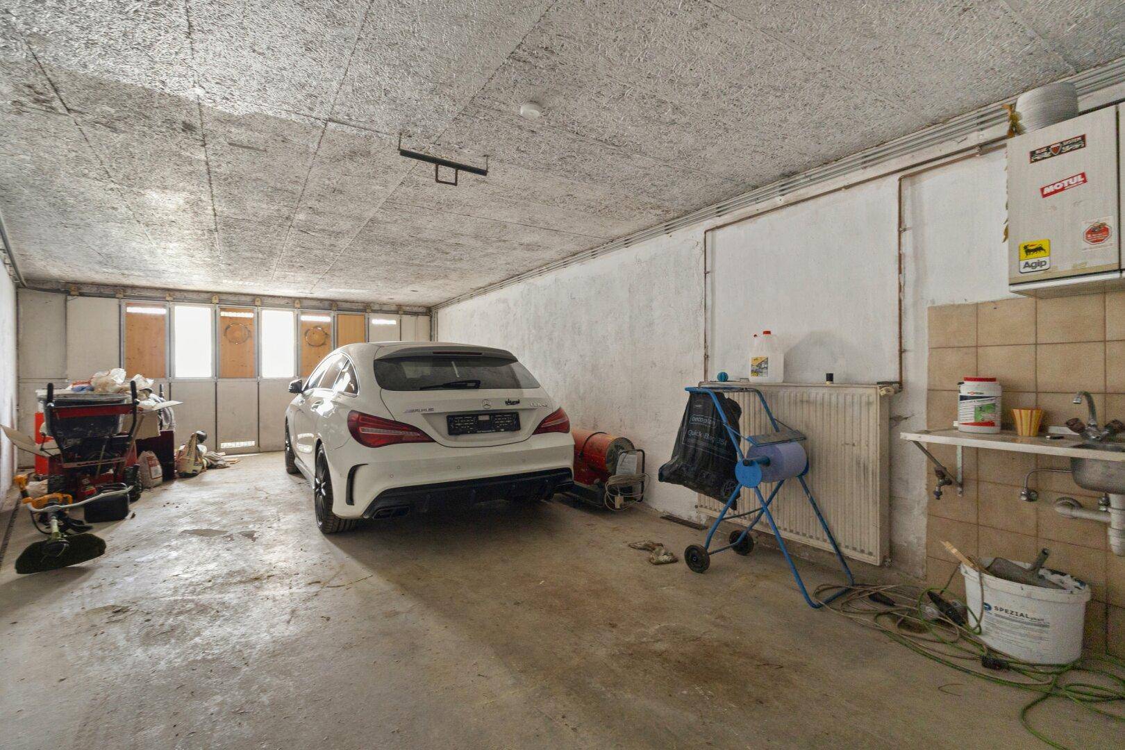 Geräumige Garage mit einem geparkten Auto, Werkzeugen und einem Waschbecken.