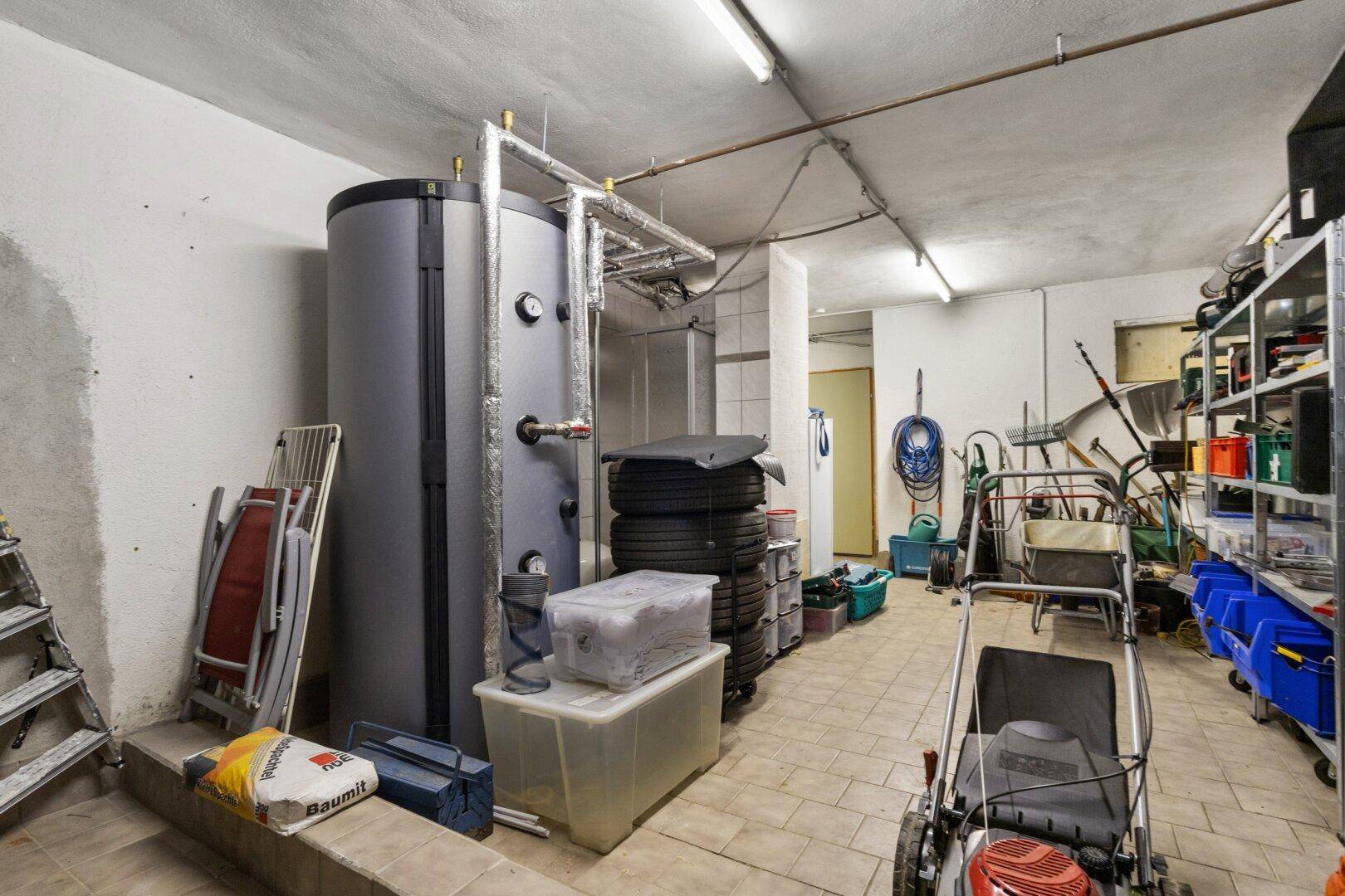 Abstellraum mit umfangreichen Regalsystemen und einem großen Warmwasserspeicher.