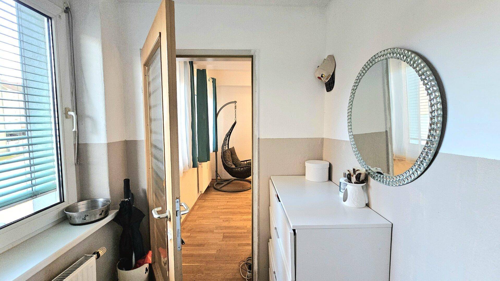 Heller Flur mit Spiegel und Kommode, der zu einem weiteren Zimmer führt.