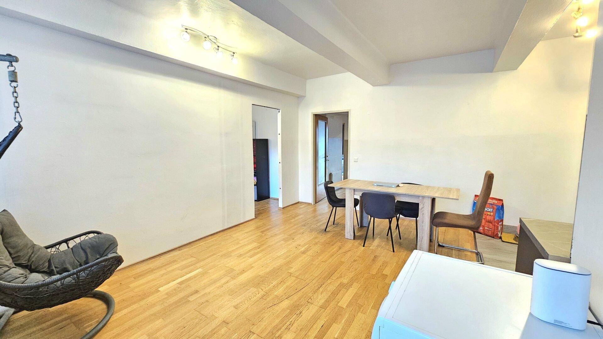 Heller Wohn- und Essbereich mit Holzboden und einem modernen Hängesessel.