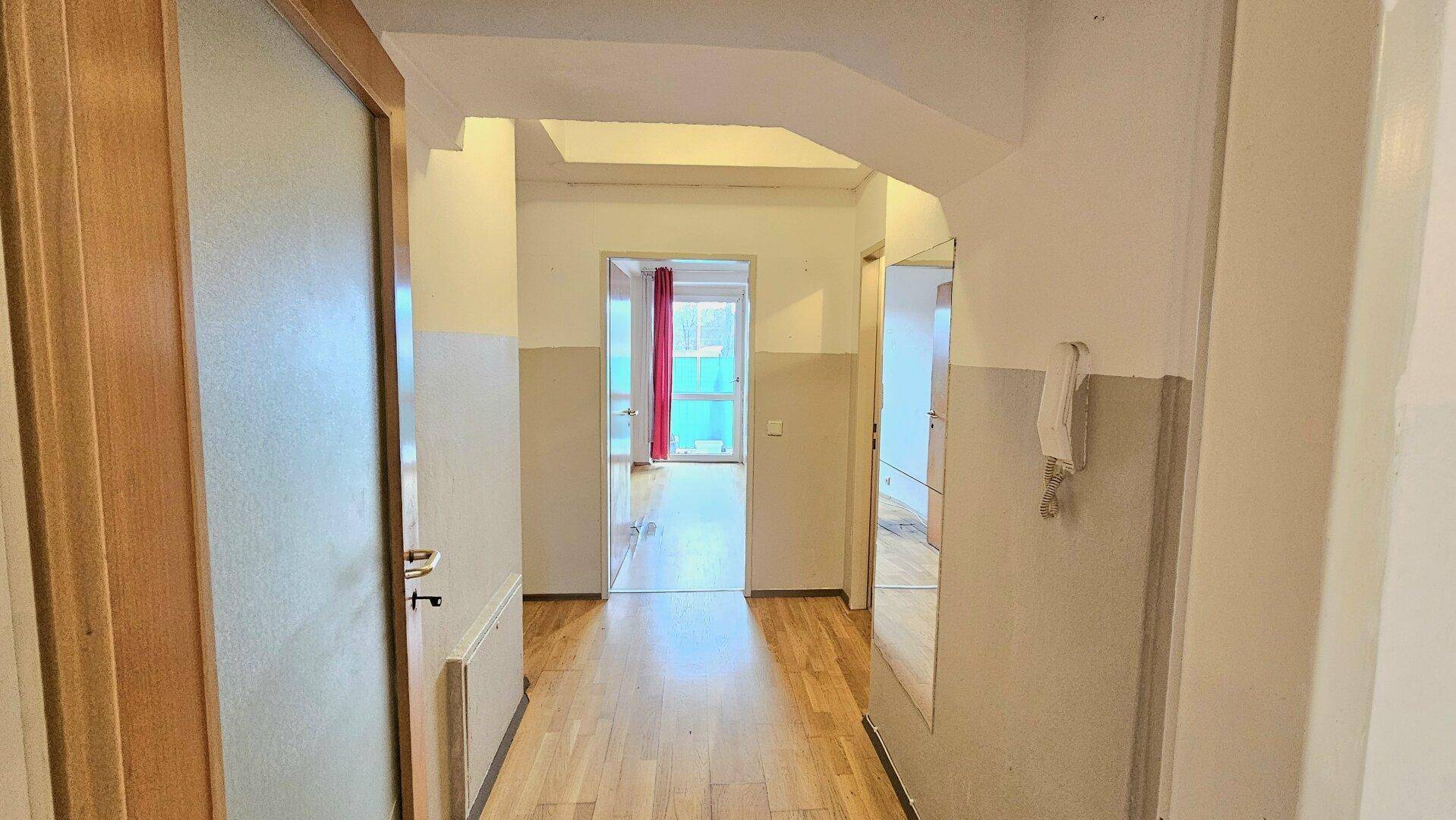 Langer Flur mit Holzboden und Zugang zu verschiedenen Zimmern der Wohnung.