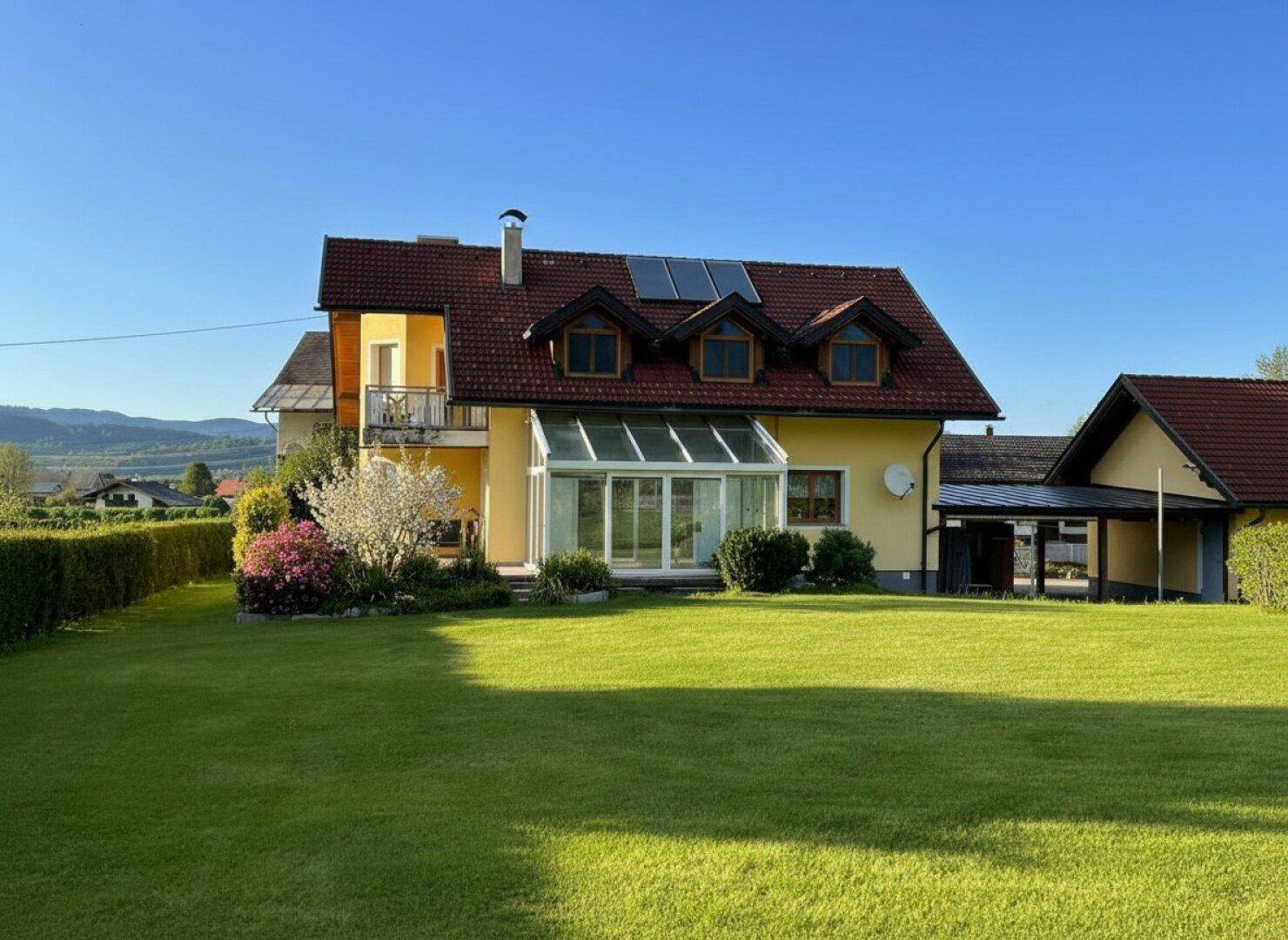 Einfamilienhaus mit Wintergarten, Balkon, Photovoltaikanlage und großem Rasen im Grünen.