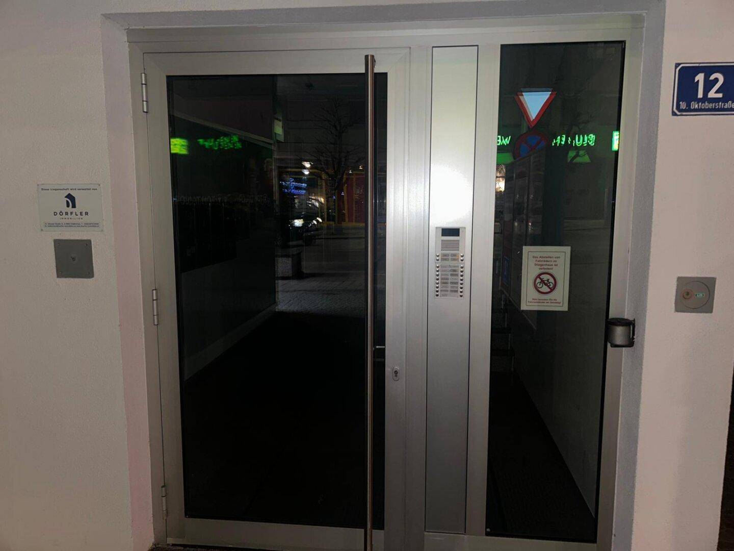 Moderner Eingangsbereich des Geschäftsgebäudes mit Glastüren und Gegensprechanlage.